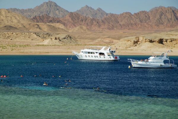 White snorkeling boats anchored in turquoise waters of Ras Mohammed National Park, ready for Sharm Blue Excursions guests to explore the Red Sea reefs