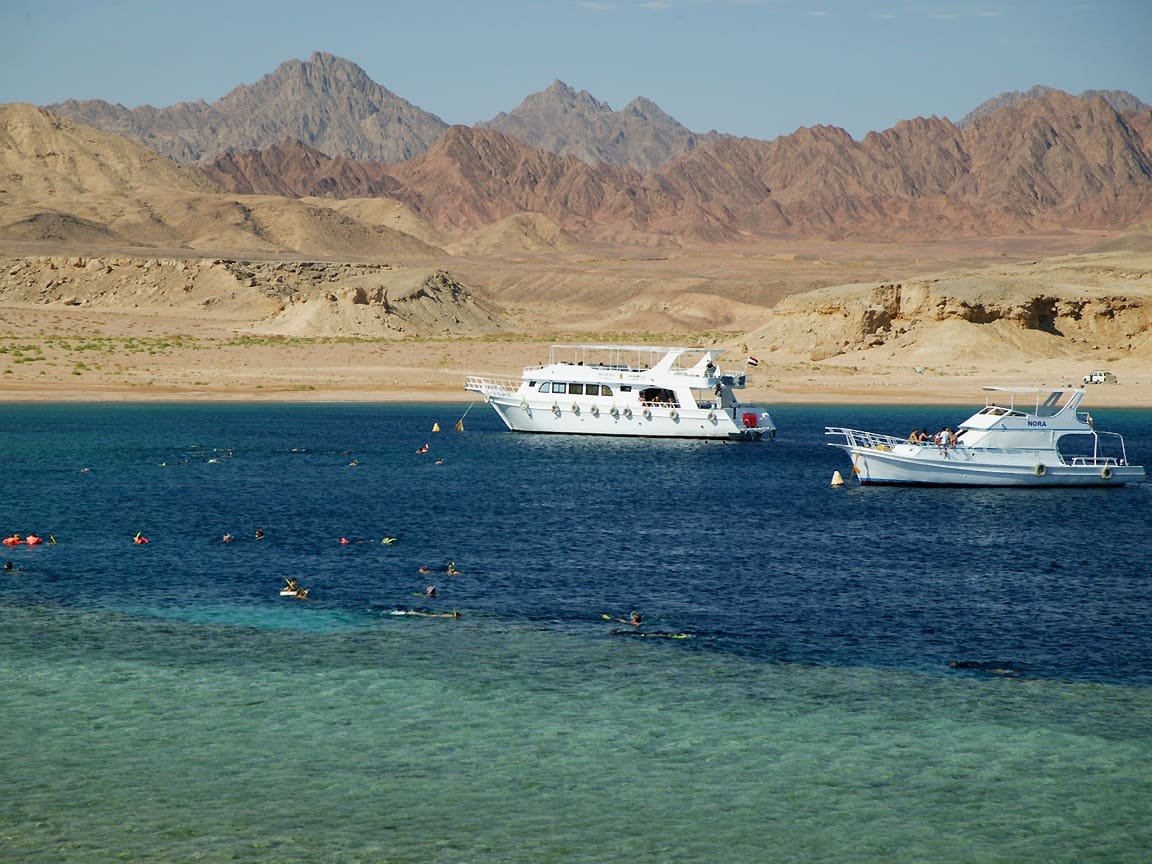 White snorkeling boats anchored in turquoise waters of Ras Mohammed National Park, ready for Sharm Blue Excursions guests to explore the Red Sea reefs